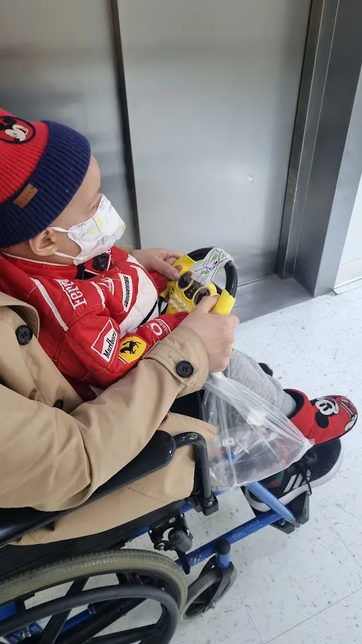 Seth i rullstol med en leksaksratt på sjukhuset